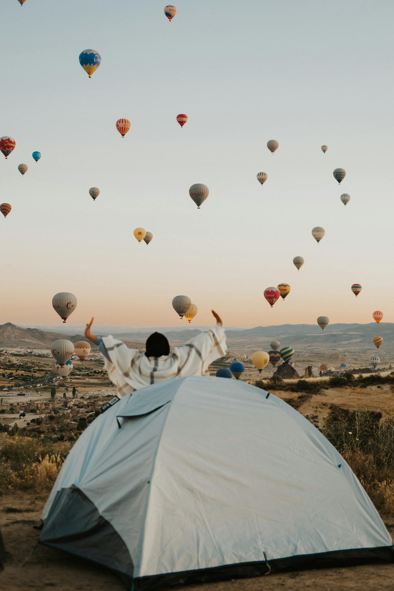 A breathtaking view of hot air balloons rising over a tent at sunrise, capturing a sense of adventure and serenity.