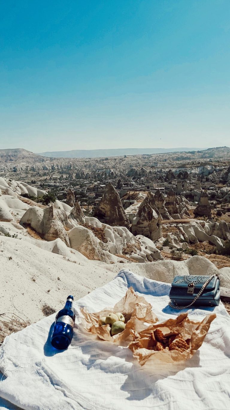Enjoy a picturesque picnic in Cappadocia with a backdrop of iconic rock formations under a bright blue sky.