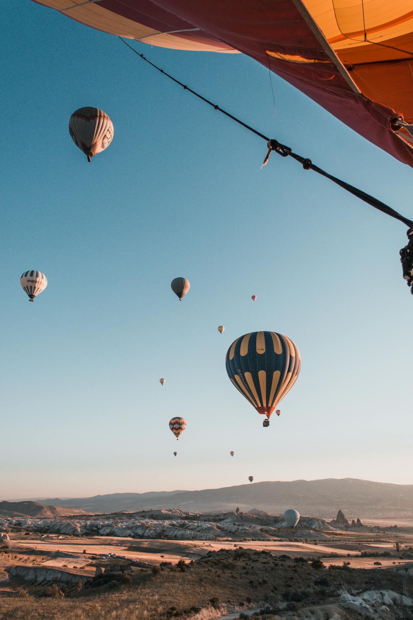 Scenic view of colorful hot air balloons floating over Cappadocia's unique landscapes during sunrise.